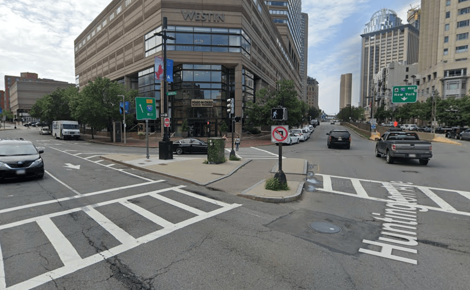 A wide intersection of two multi-lane city streets lined with high-rise buildings.
