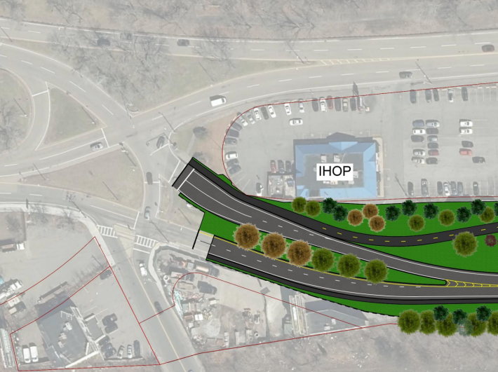An aerial view of highway plans with greyed-out satellite imagery under an illustration of new roads and a bike path that run from the right edge of the image to the center, at the edge of a large traffic circle. Above the new road drawing is a blue-roofed building labelled "IHOP"