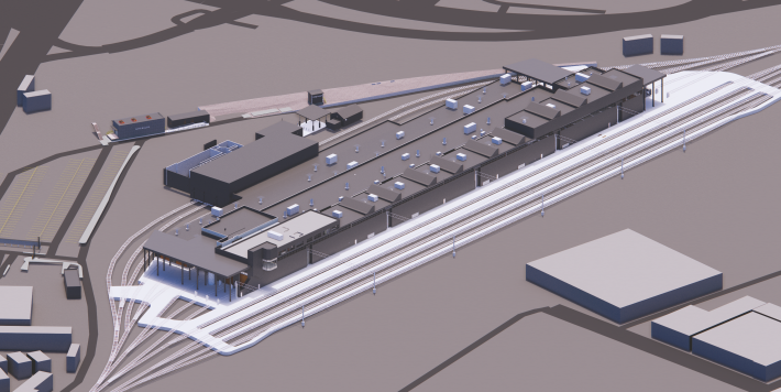 A bird's-eye view rendering of a large train shed, a long, rectangular low-rise building with numerous tracks leading into the facility. The building is surrounded by additional tracks in the foreground.