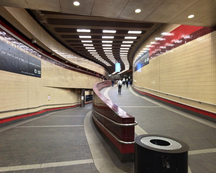 Two curving ramps lead to an upper level (right) and lower leve (left) in a subway station.