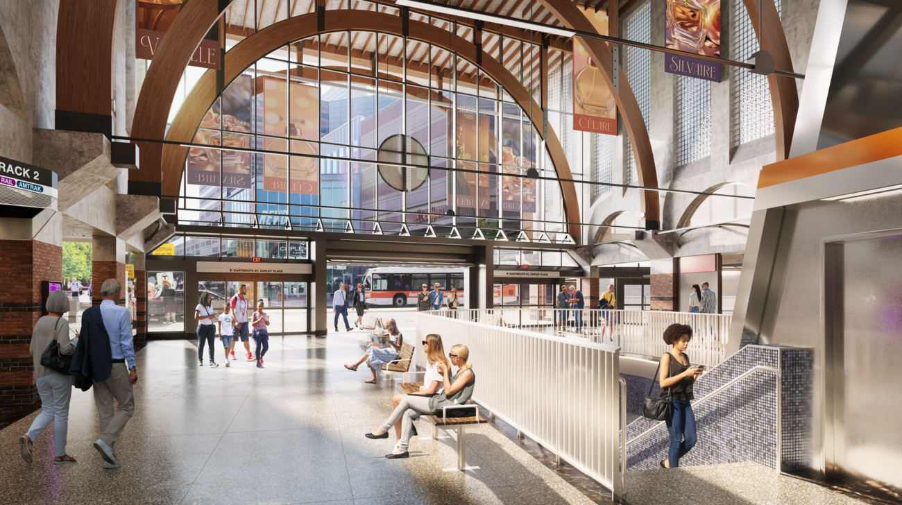This rendering of Back Bay is from inside the station facing the street. A glass wall shows the Back Bay Logan Express bus passing by. Inside, there is a staircase with blue tiling that leads down to the train platforms. Commuters are walking up the stairs, through the station, and sitting down.