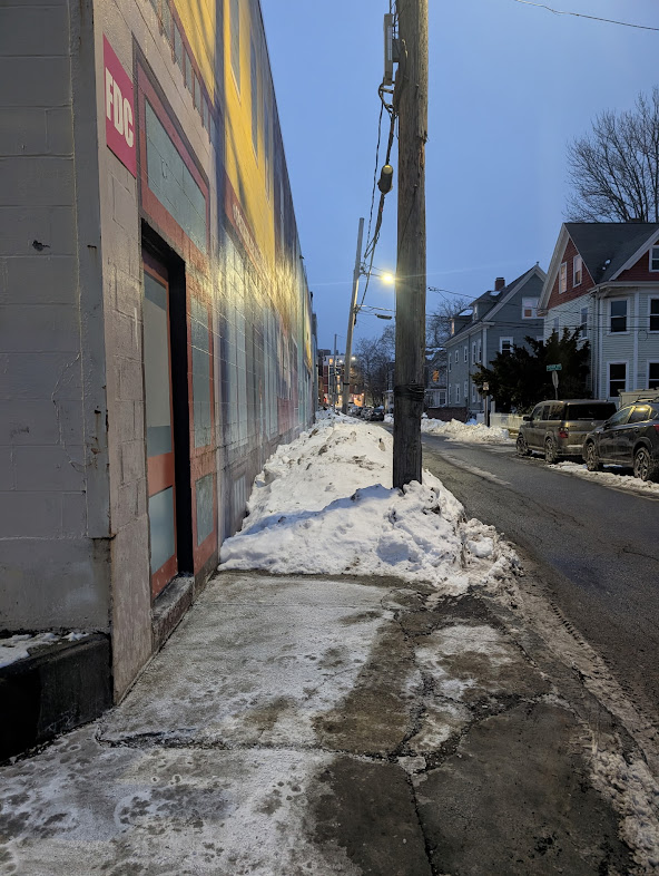 A very narrow, unshoveled sidewalk on Orchard Ave behind a Star Market.