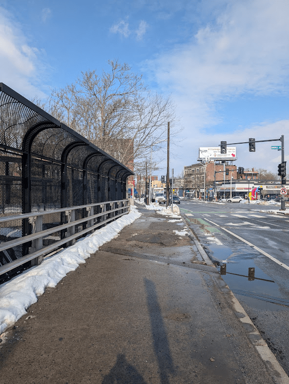 A wide-angle view of a Porter Square intersection showing both cleared sidewalks and high snowbanks.